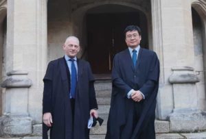photo of two men wearing black academic gowns and suits