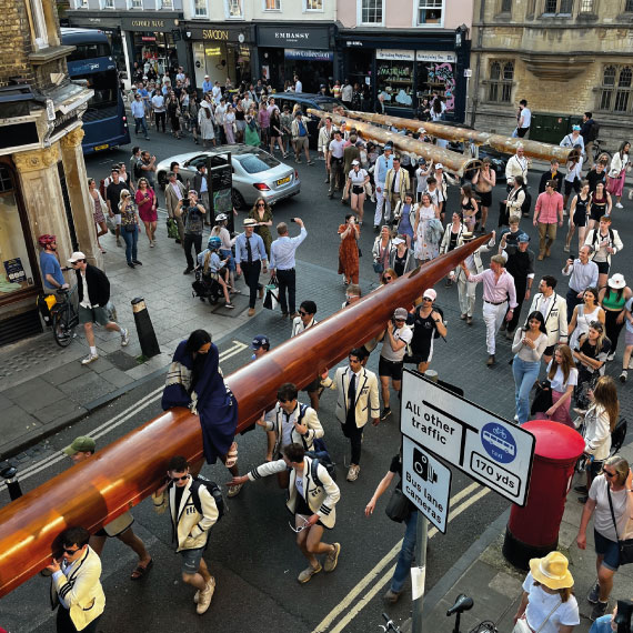 Crowds of people following students carrying boat