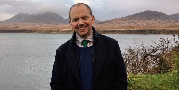 Lord Cameron standing in front of a lake.