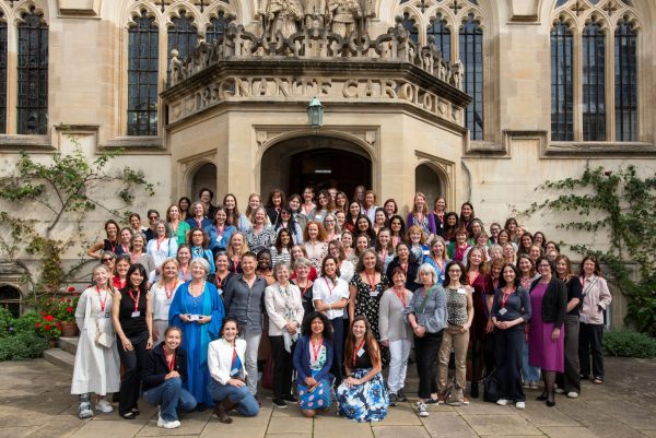A group of women posing in front of the steps of the First Quad of Oriel College